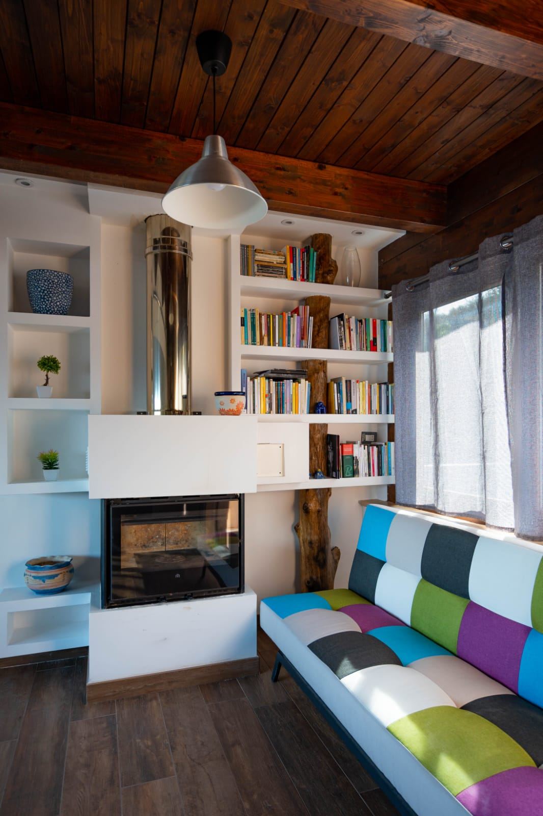Soggiorno con camino e divano multicolore del B&B Mythos